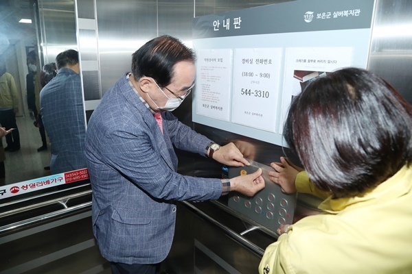 정상혁 보은군수가 보은군 실버복지관 엘리베이터 안 층별 버튼에 향균필름을 붙이고 있다.